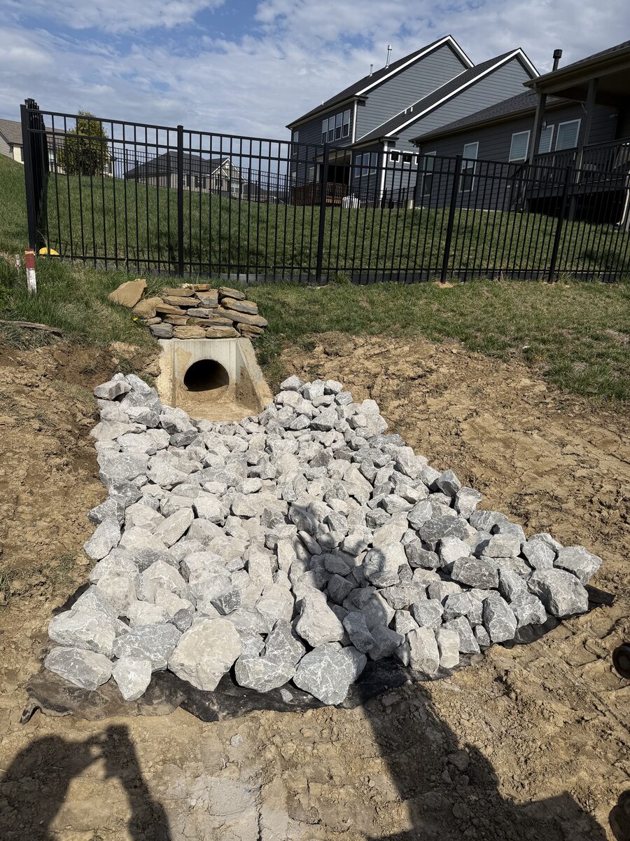 Riprap drainage outlet with concrete headwall — residential yard