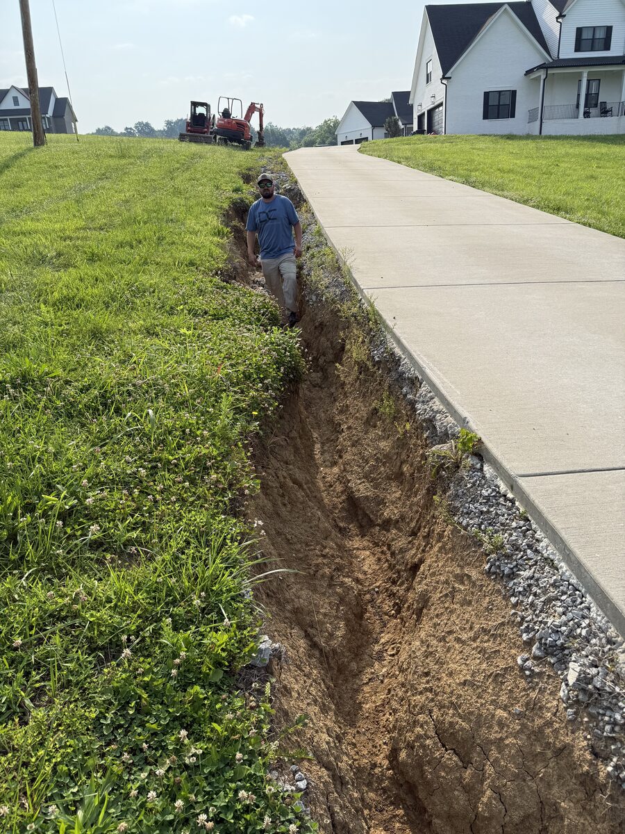 Deep washout channel carved by runoff alongside driveway — before erosion control work