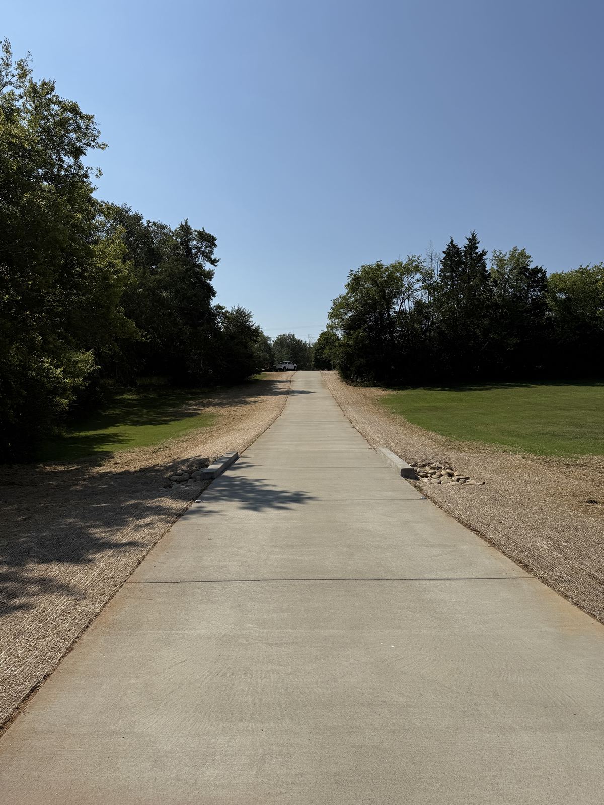 Full length of new concrete driveway after grade-out with straw on both shoulders &mdash; Greenbrier TN