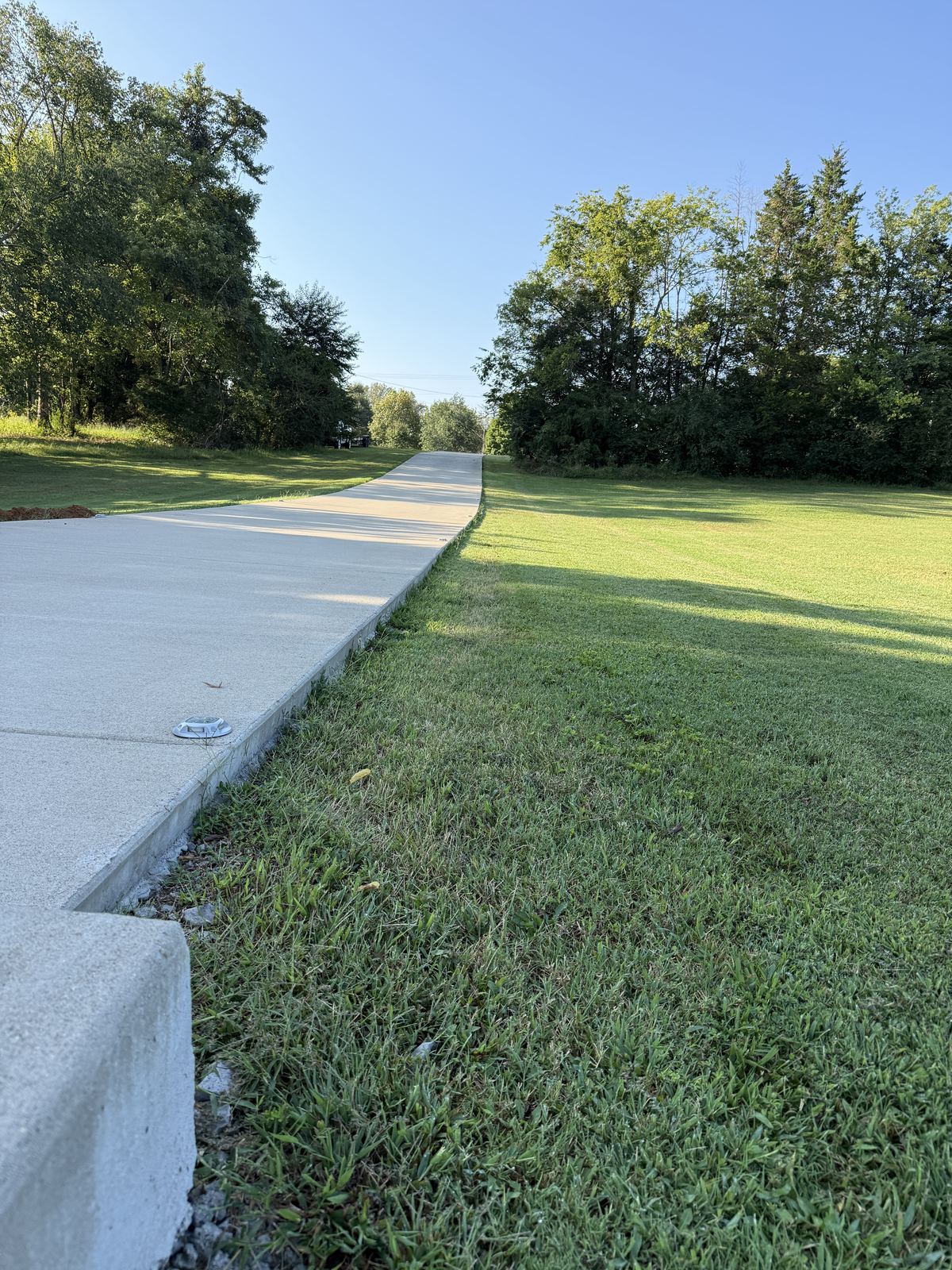 Long run of new concrete driveway with exposed edge and low ground alongside &mdash; Greenbrier TN