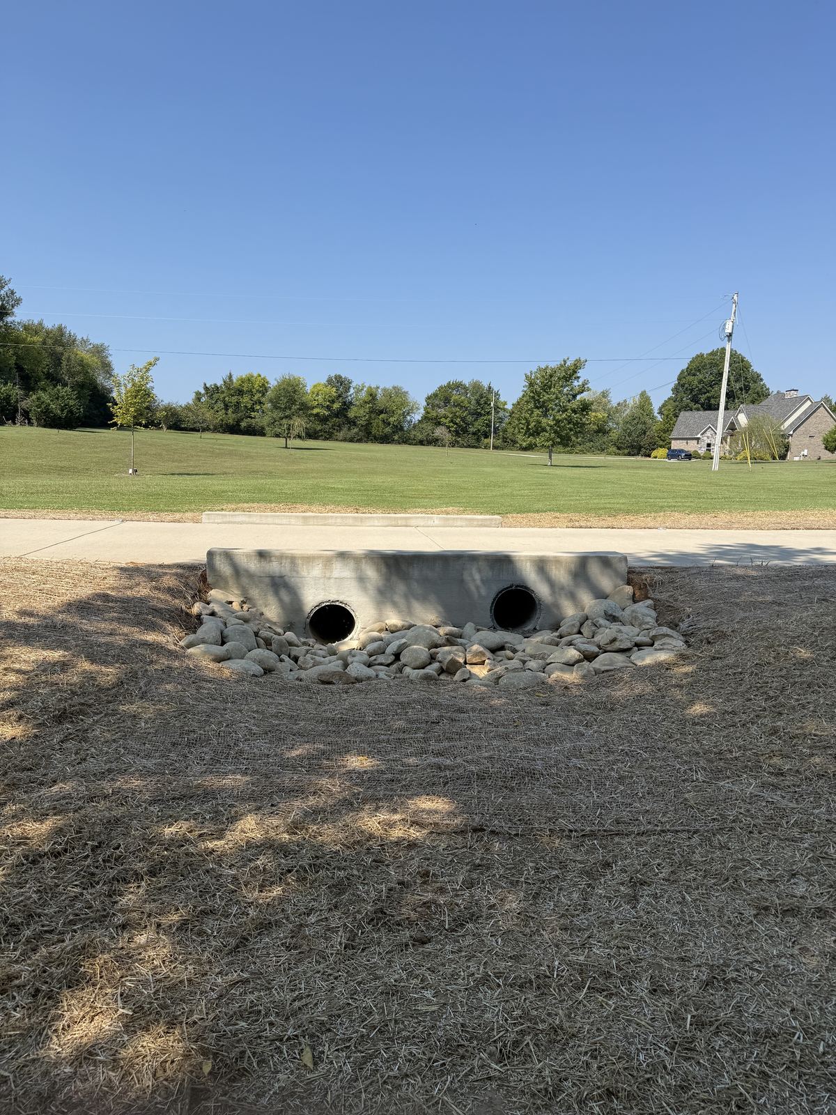 Twin driveway culvert pipes with regraded outlet armored with 7 to 14 inch Pigeon River rock, straw around &mdash; Greenbrier TN