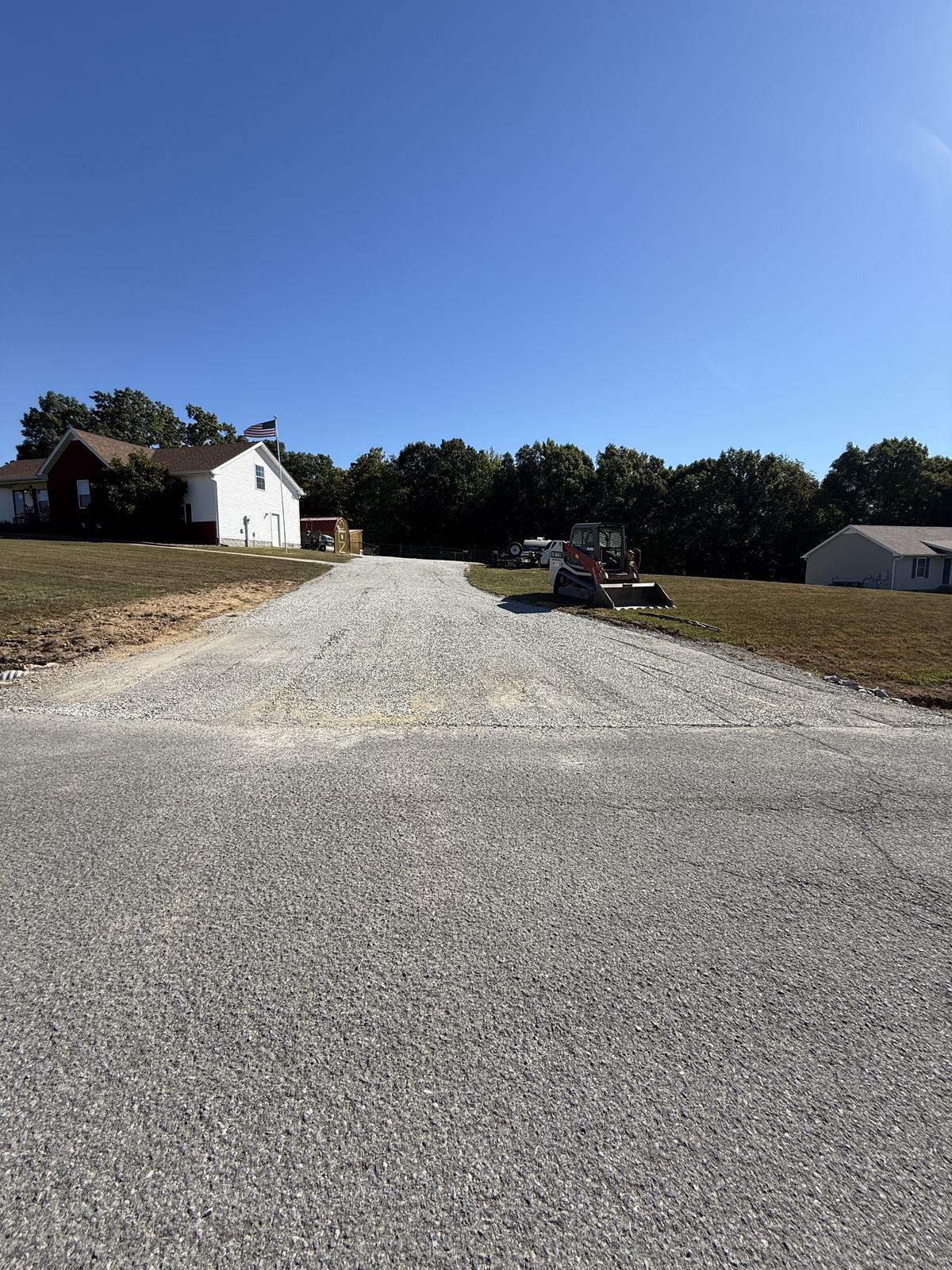 Same driveway rebuilt with fresh stone and rolled smooth, track loader on site &mdash; Cross Plains TN, after