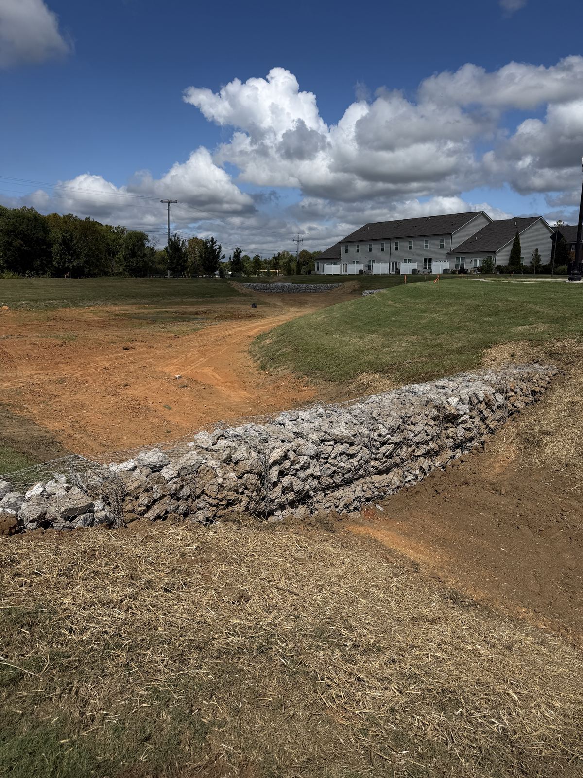 Gabion basket forebay wall with rebuilt red dirt pond bottom behind it &mdash; Lebanon TN