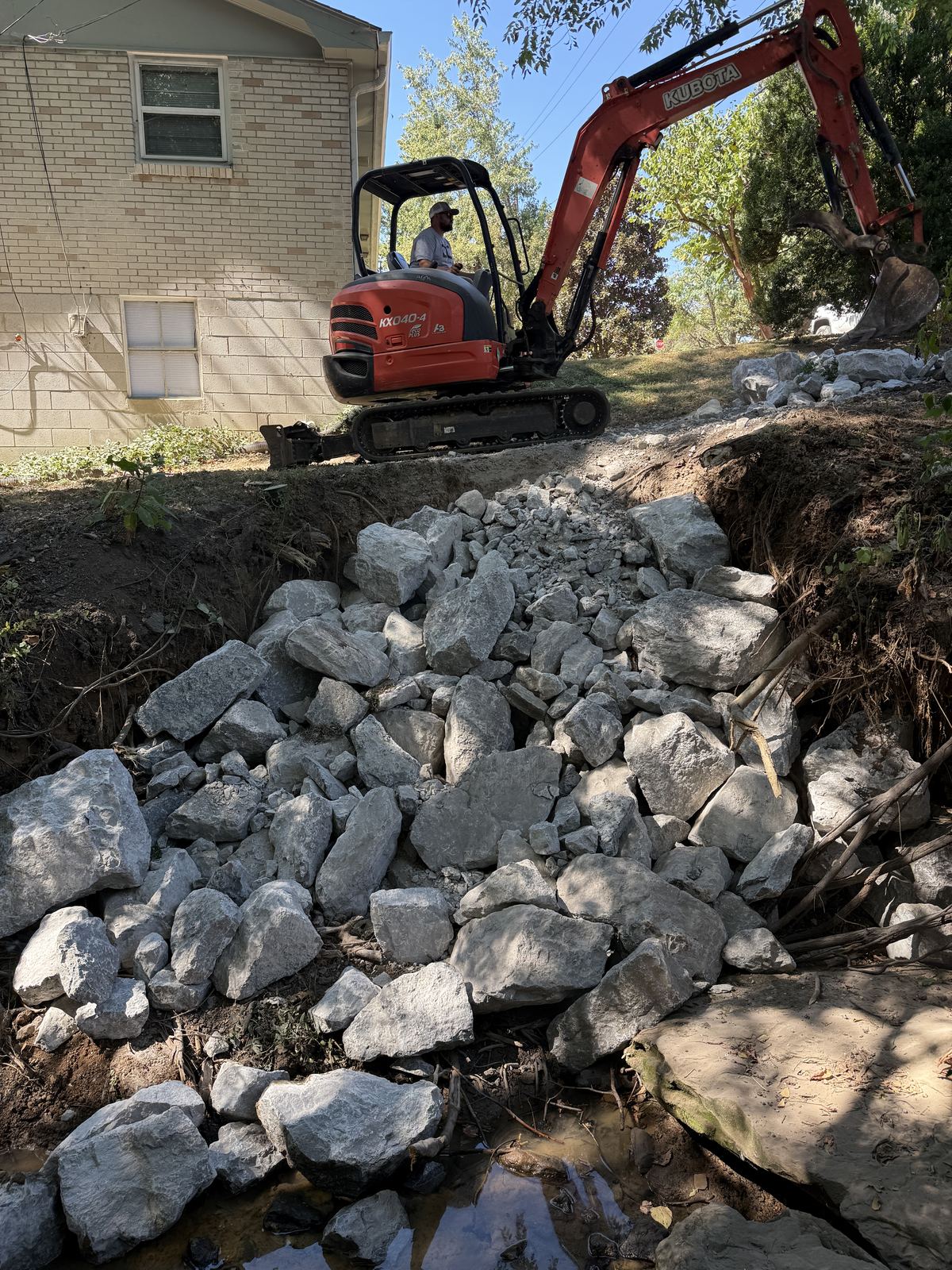 Large Class B riprap stone armoring an eroded creek bank beside a house &mdash; Nashville TN
