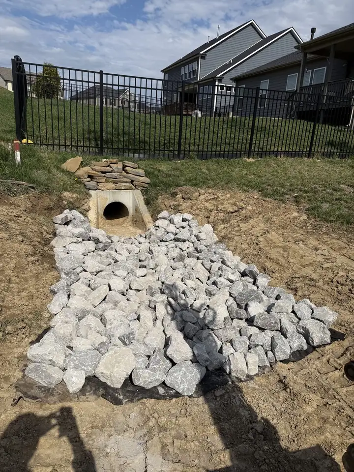 Riprap drainage outlet with concrete headwall — residential yard